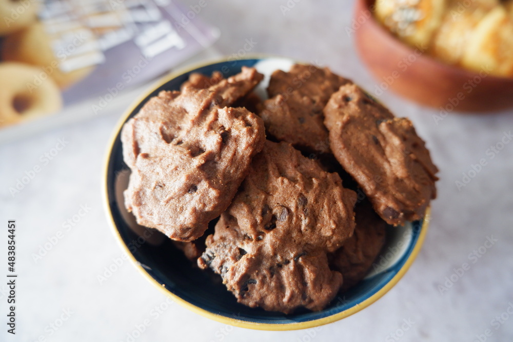 homemade chocolate cookies in a bowl, on a gray background. snacks, biscuits, made from flour, eggs, and sugar are eaten at tea time. snack time. close up homemade chocolate cookies in a bowl, on a gray background. snacks, biscuits, made from flour, eggs, and sugar are eaten at tea time. snack time. close up