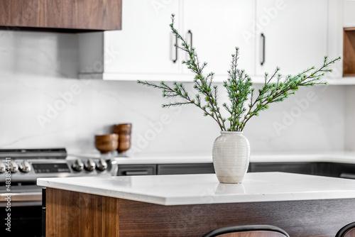 Midcentury modern kitchen with black and white cabinets, matte black fixtures, white quartz countertops and backsplash and walnut wood furniture interior design