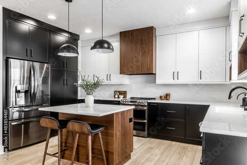 Midcentury modern kitchen with black and white cabinets  matte black fixtures  white quartz countertops and backsplash and walnut wood furniture interior design