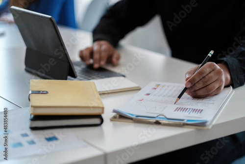 Businessman discussing analysis charts or graphs on desk table and using laptop computer. Close up male analysis and strategy concept