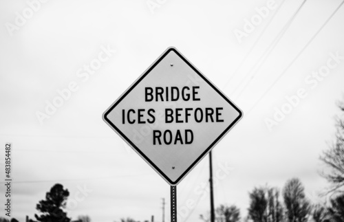 A black and white bridge ices before the road sign 
