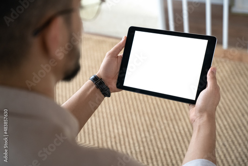 Closeup of Indian man holding digital tablet sitting on sofa at home office
