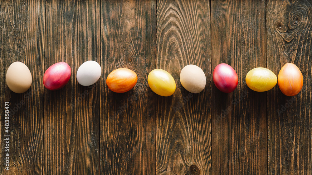 Obraz premium Multicolored Easter eggs on a wooden background. Easter background. Copy space. Easter eggs flat lay on rustic table. Easter concepts