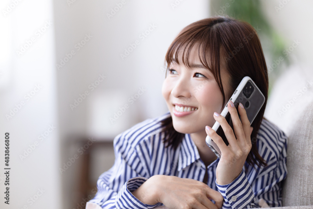 ソファに寝転んで電話する女性 ソファに寝転んで電話する女性