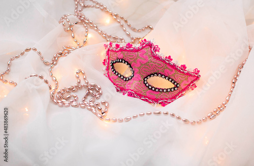 Traditional carnival mask Mardi gras pink beads on a white background. Venetian masks. An invitation to a party, a greeting card, the concept of celebrating the Carnival of Venice