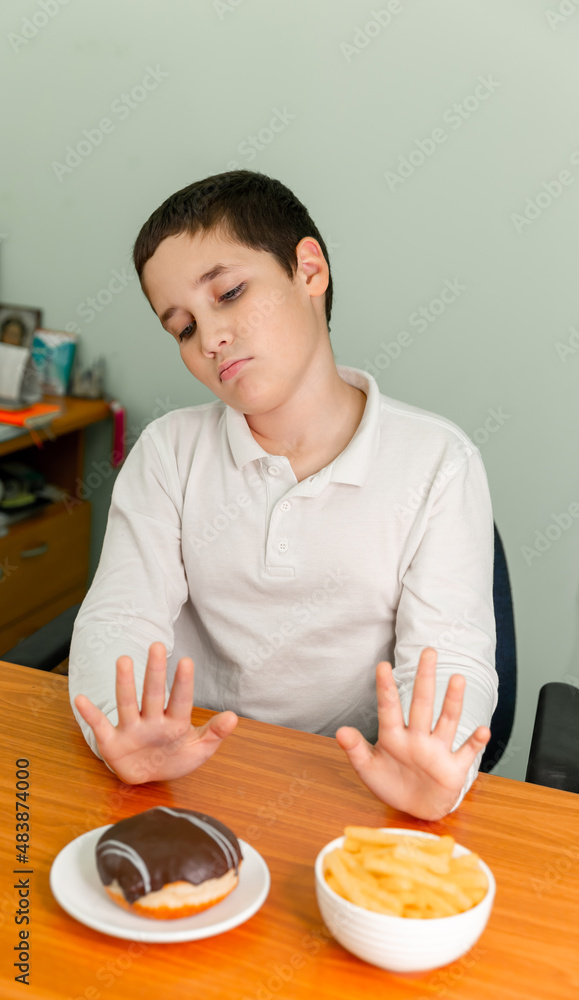 Overweight boy rejecting unhealthy food. Child refuses to eat unhealthy fast food. Healthy eating and active lifestyle. Kids diet. Poor appetite. Stop gesture. Do not force the child to eat.