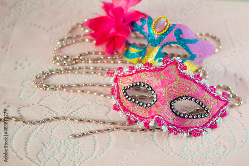 festive, colorful Mardi Gras or carnival mask and beads on a pink background. Venetian masks. An invitation to a party, a greeting card, the concept of celebrating the Carnival of Venice