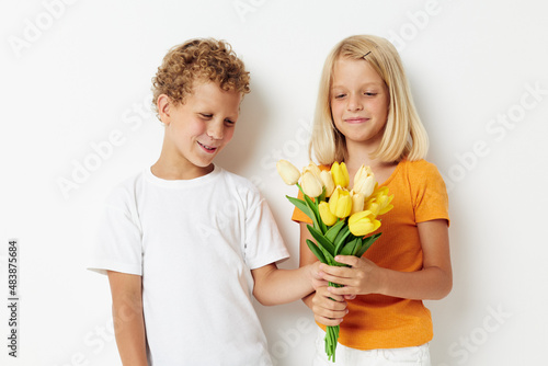 two joyful children with a bouquet of flowers gift birthday holiday childhood light background