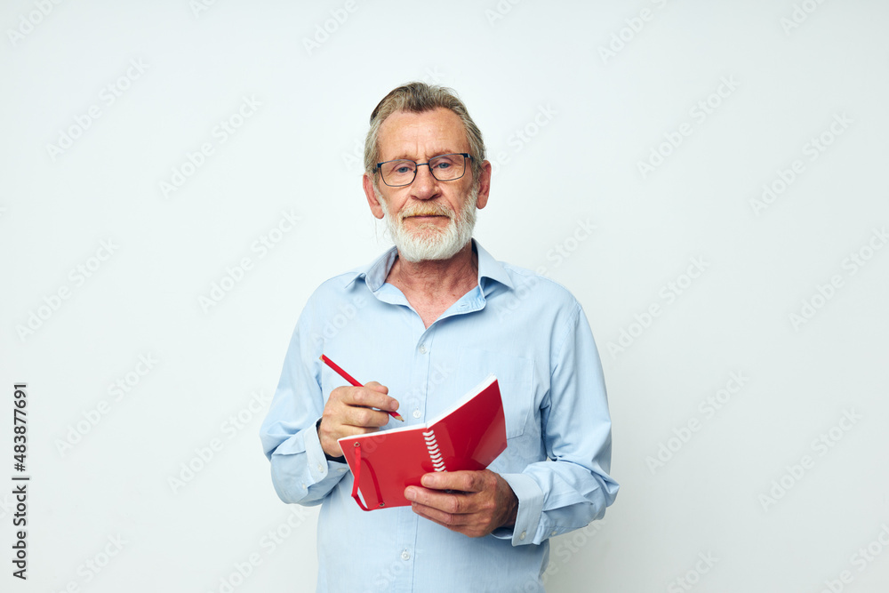 Photo of retired old man red notepad writing light background Photo of retired old man red notepad writing light background
