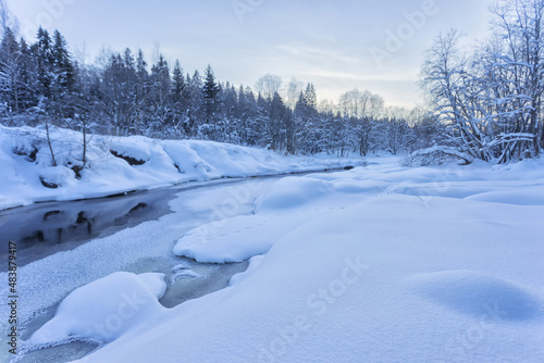 Fototapeta Naklejka Na Ścianę i Meble -  Snow banks of forest river at winter sunset. Winter landscape