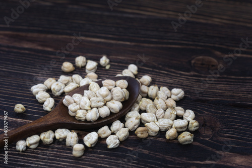 Chickpeas in a wooden spoon on a dark wooden background