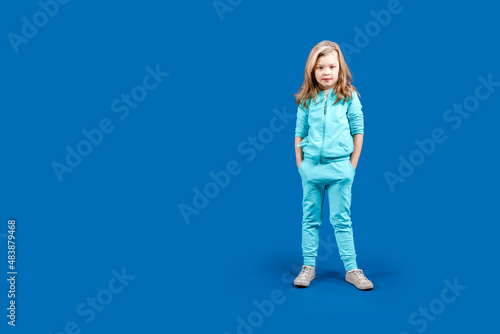 Copy space. Girl athlete. A child girl in a tracksuit stands in full growth
