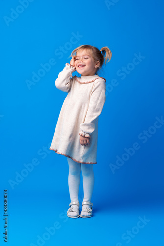 Full length portrait of a little girl standing on blue backgorund
