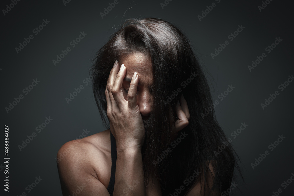 Depression or domestic violence concept: Unhappy woman hiding her face with one hand. Sadness and boredom. 8 march Women's day or women's rights concept. Dizziness or migraine problem. Stop violence.