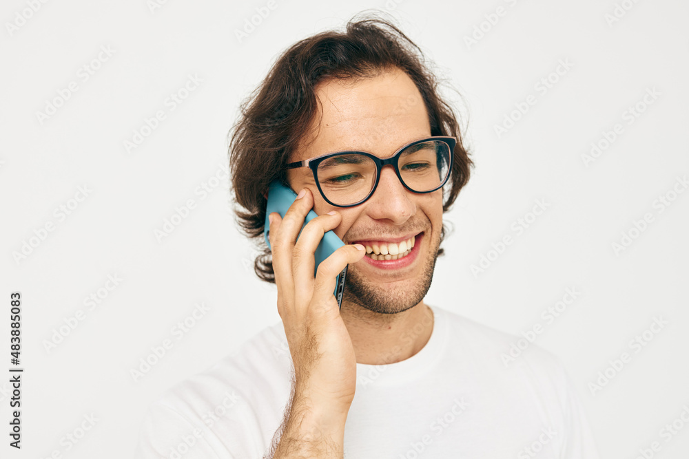 Attractive man in a white T-shirt communication by phone light background