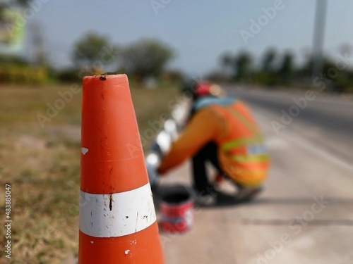 Blurred image of a worker painting the edge of a sidewalk