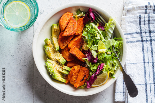Baked sweet potato slices with avocado and green salad. Healthy vegan food concept.