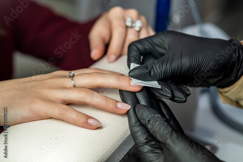 client sitting in the salon where her manicurist is doing nail cleaning during the epidemic.
