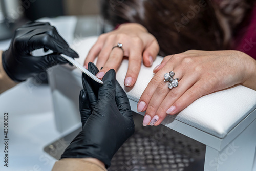 a manicurist in special gloves saws off a new client's nails during an epidemic.