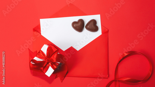chocolates, love letter envelope, gift box on red background . Valentine's day celebration concept. Copy space. Flat lay