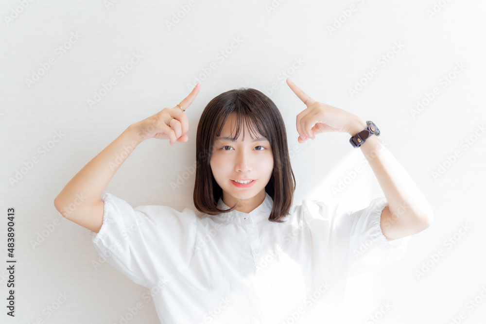 両手の指で頭上を指す女性