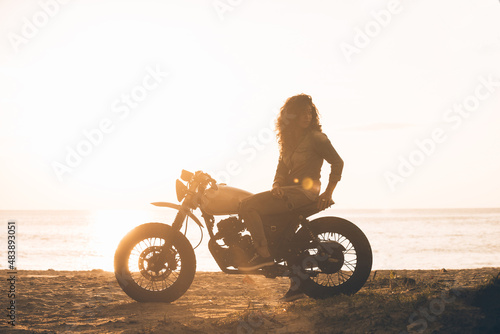 Fotografie Beautiful girl having fun driving her custom cafe racer motorcycle, enjoying the