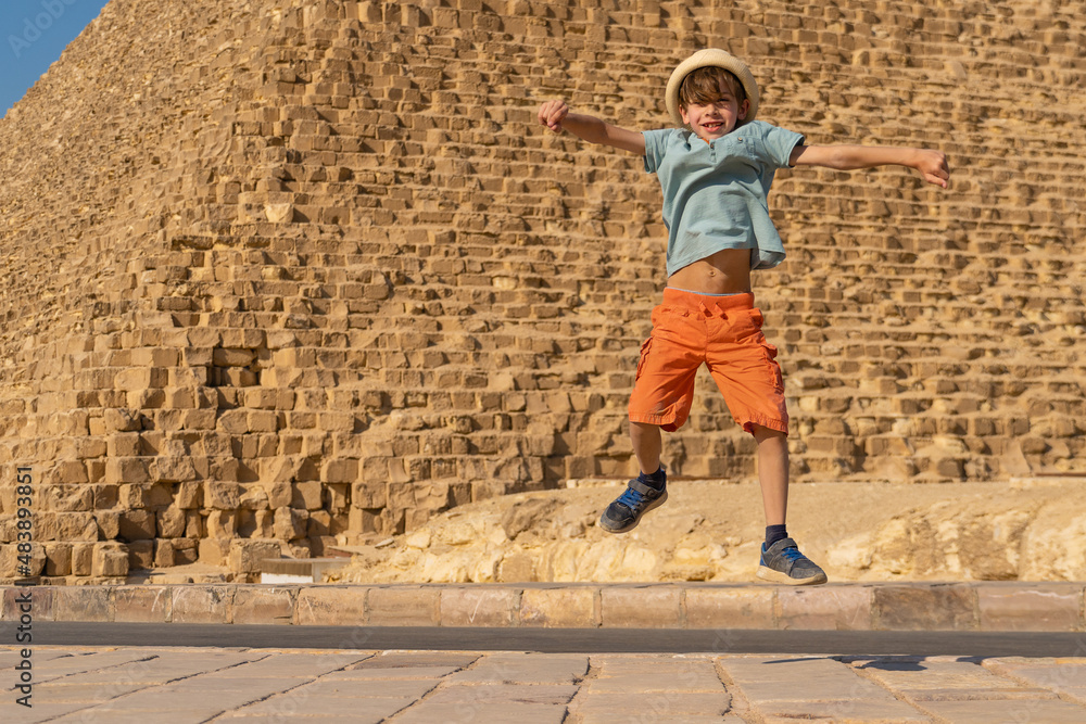 Happy boy jumping in front of the Cheops pyramid on the Giza plateau.
