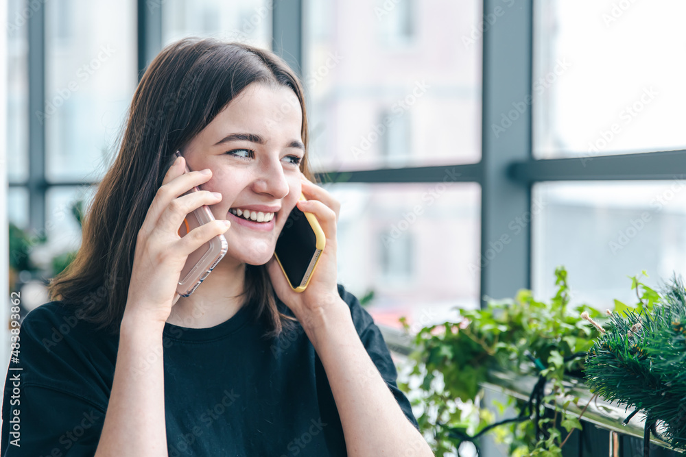 Portrait of a smiling young woman talking on two phones. Portrait of a smiling young woman talking on two phones.