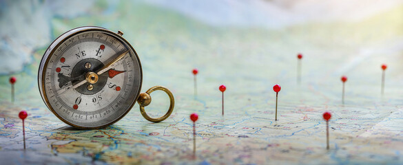 Magnetic compass  and location marking with a pin on routes on world map. Adventure, discovery, navigation, communication, logistics, geography, transport and travel theme concept background.