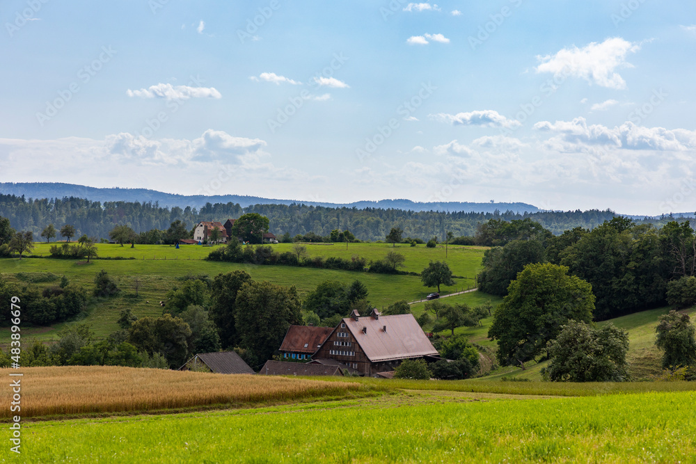 View in cloudy sky over pastures and meadows towards forest on Swabian Alb View in cloudy sky over pastures and meadows towards forest on Swabian Alb