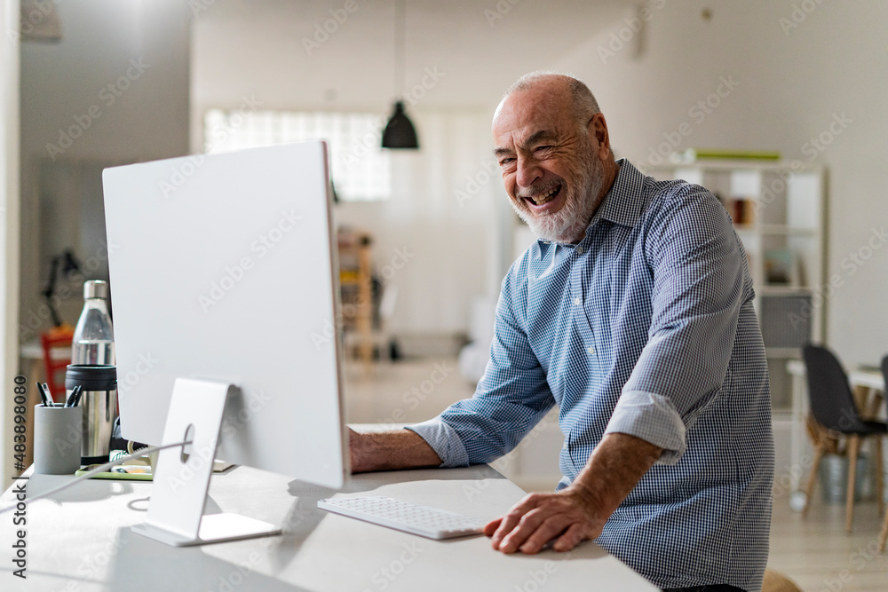 Cheerful senior freelancer with computer working from home Cheerful senior freelancer with computer working from home