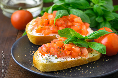 Tasty savory tomato Italian appetizers, or bruschetta, on slices of toasted baguette garnished with basil, close up