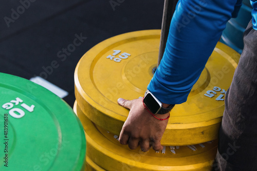 Hands of athlete removing weight plates in gym photo