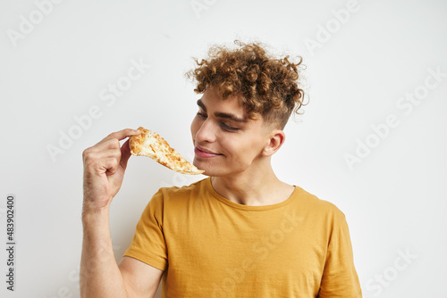 handsome young man in a yellow t-shirt eating pizza Lifestyle unaltered