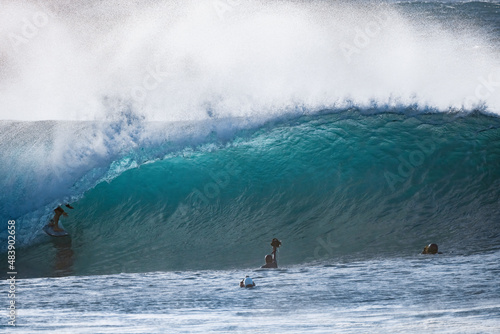 Surfer riding a barrel wave on a short board and photographers taking pictures of him