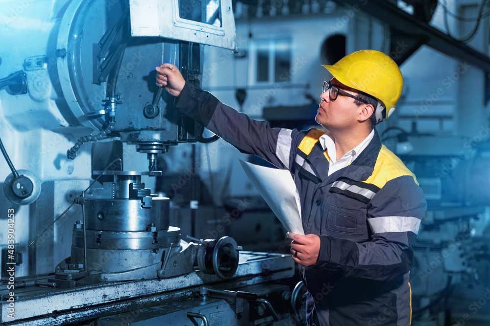 a worker at a large machine-building plant adjusts a drilling machine a worker at a large machine-building plant adjusts a drilling machine