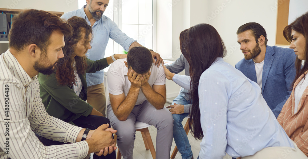 People in group therapy comforting desperate crying man. Concerned ...