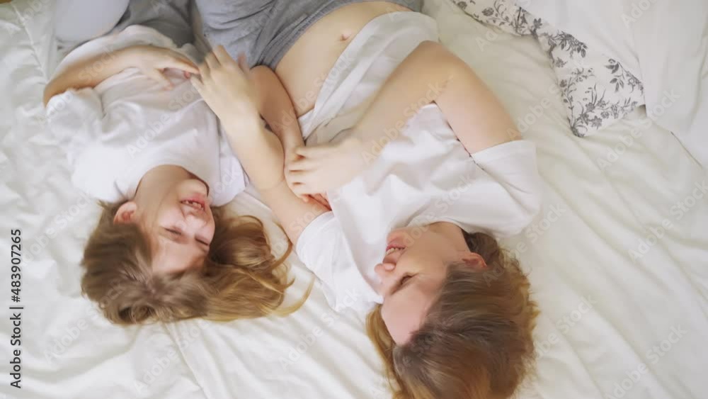 view top. mother and daughter laughs with tickling on the bed. games of children
