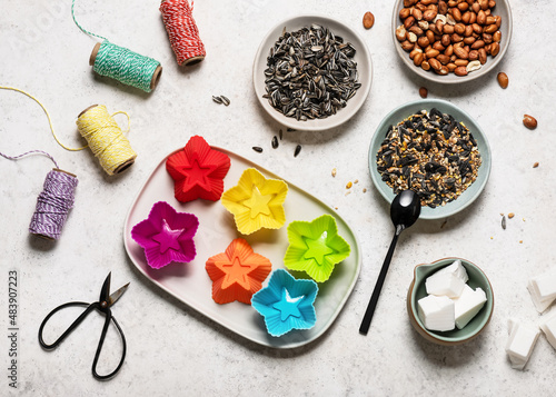 Top view of workplace with colorful silicone muffin pans, organic peanuts, sunflower seeds, coconut fat and tools to create bird feeder cakes. Decorative home handmade concept.