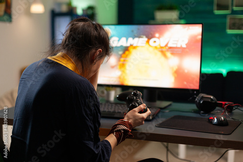 Angry woman playing online video games with joystick. Gamer using controller on computer to play internet games and losing. Disappointed person with electronic gaming equipment.