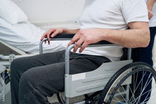 Professional physiotherapist and man with disability in hospital ward