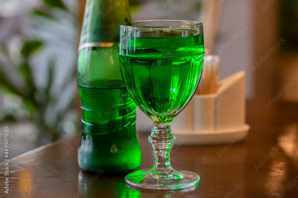 transparent glass with a wine drink on a wooden table. Bright green drink in a glass transparent glass with a wine drink on a wooden table. Bright green drink in a glass