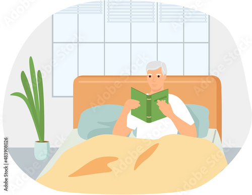 Cute man in pajamas reading literature on his bed comfortably. Book lover concept with young man lying relax on sofa and reading book. Concept of homeward and comfort. Person relaxes after work