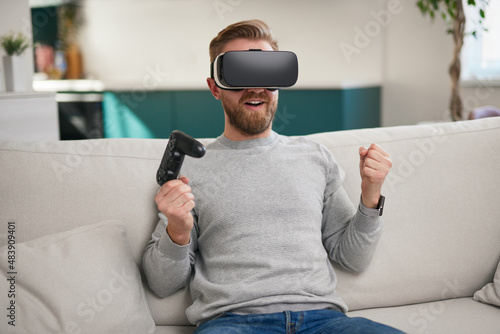 Happy man in VR goggles celebrating win in game © kegfire