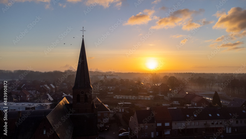 Fototapeta premium Cityscape silhouette of catholic church tower in Sint Jozef, Rijkevorsel, Belgium on a wonderful orange blue evening sky background. Cityscapes and religion concepts. High quality photo