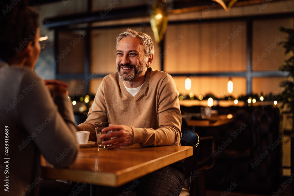 Smiling caucasian adult man, having a drink with his female partner, at a restaurant.