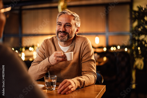 Relaxed caucasian man, holding a cup of tea, while looking at his partner.