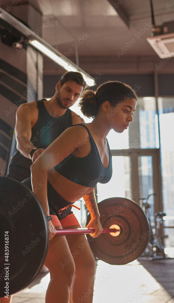 Trainer teaching girl exercising for back in gym Trainer teaching girl exercising for back in gym
