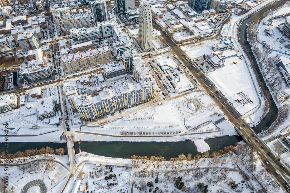 Aerial drone view of the city at winter, with houses and roads. Winter landscape