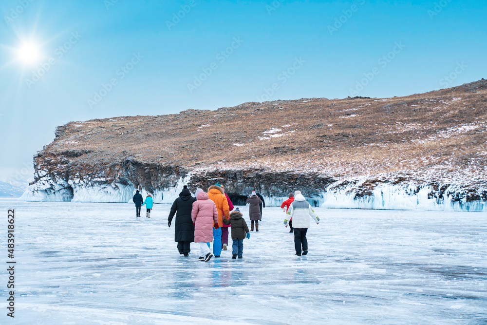 Lake Baikal. A group of tourists walks on the ice to explore the ice caves on the island of Olkhon.